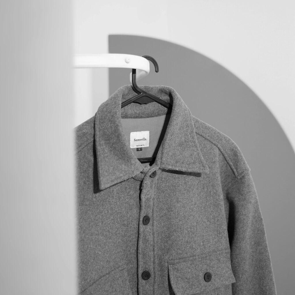 Black and white photo of a gray jacket on a hanger indoors, showcasing minimalist style.